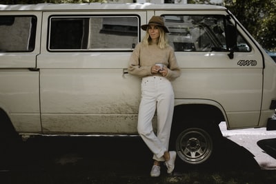 Wore cream-colored long-sleeved shirt and white trousers woman sitting on a white car
